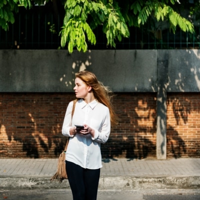 Jeune femme traversant dans la rue avec un smartphone à la main